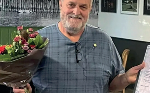 Andries de Vries met een bos bloemen en de oorkonde en de gouden speld die hij kreeg vanwege zijn jubileum. Foto Op 'e Hichte
