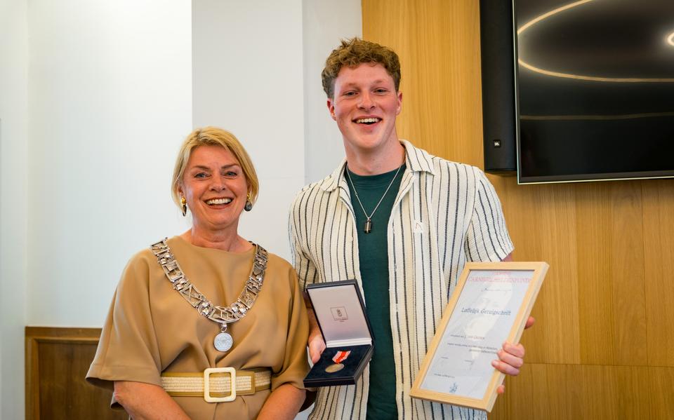 Jordy ontvangt uit handen van de burgemeester een bronzen medaille en een getuigschrift van het Heldenfonds. 